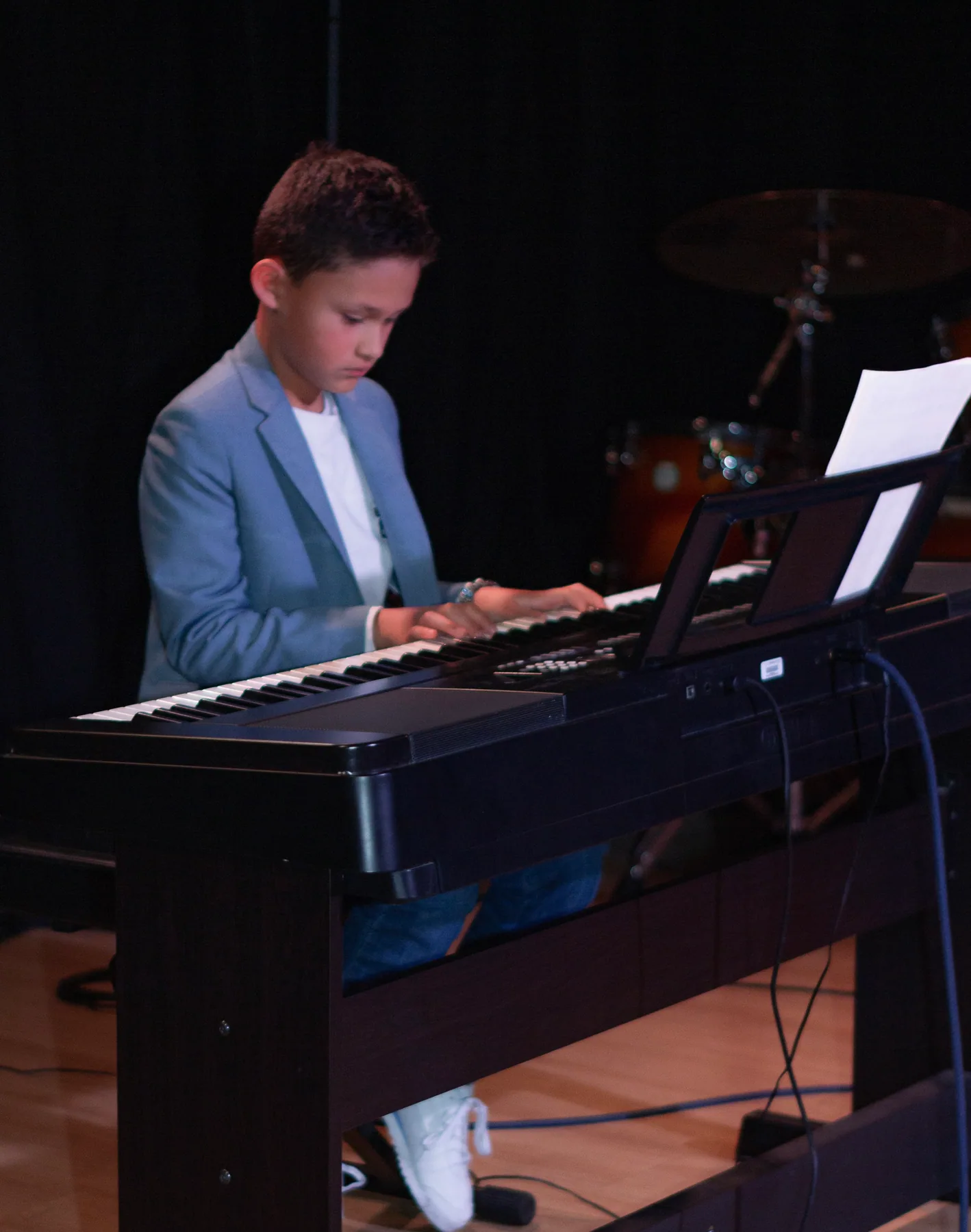 Estudiante tocando teclado en una presentación.
