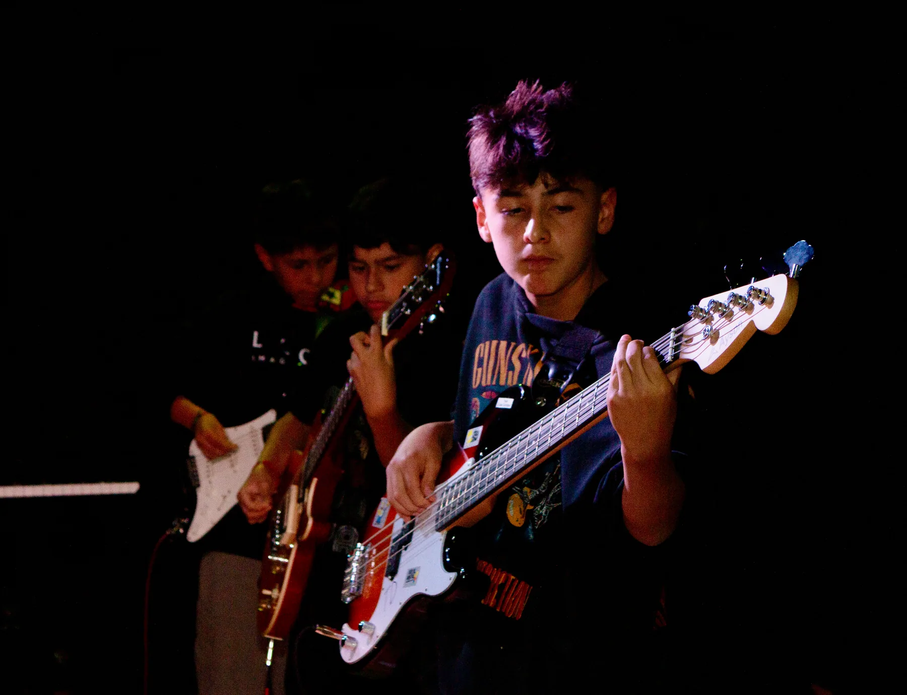 Estudiante tocando bajo eléctrico durante una presentación.