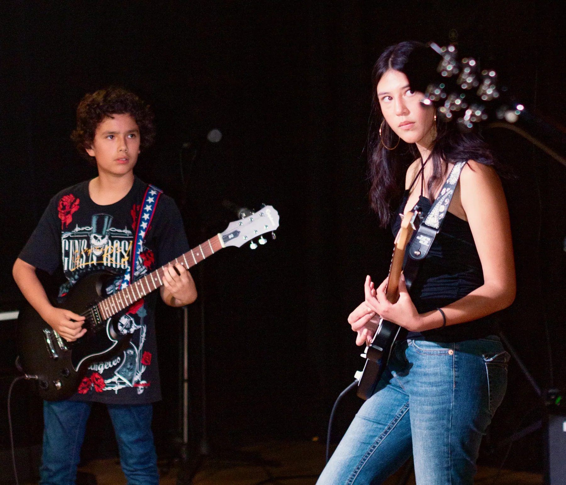 Dos estudiantes tocan guitarra eléctrica en el escenario.