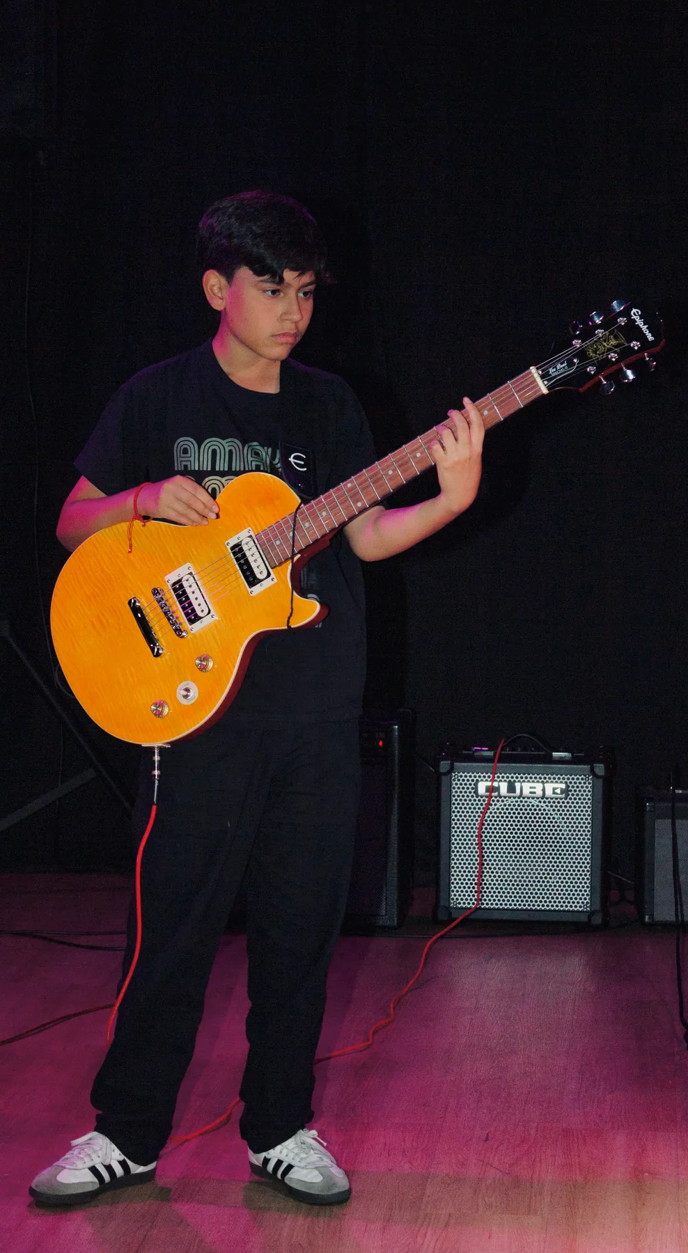 Estudiante toca una guitarra eléctrica amarilla.