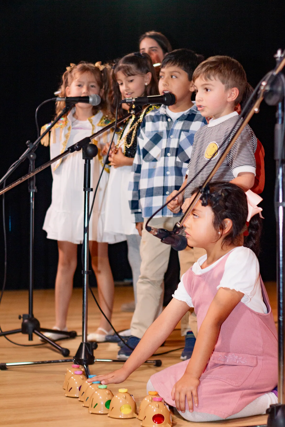 Grupo de niños cantando juntos frente a micrófonos.