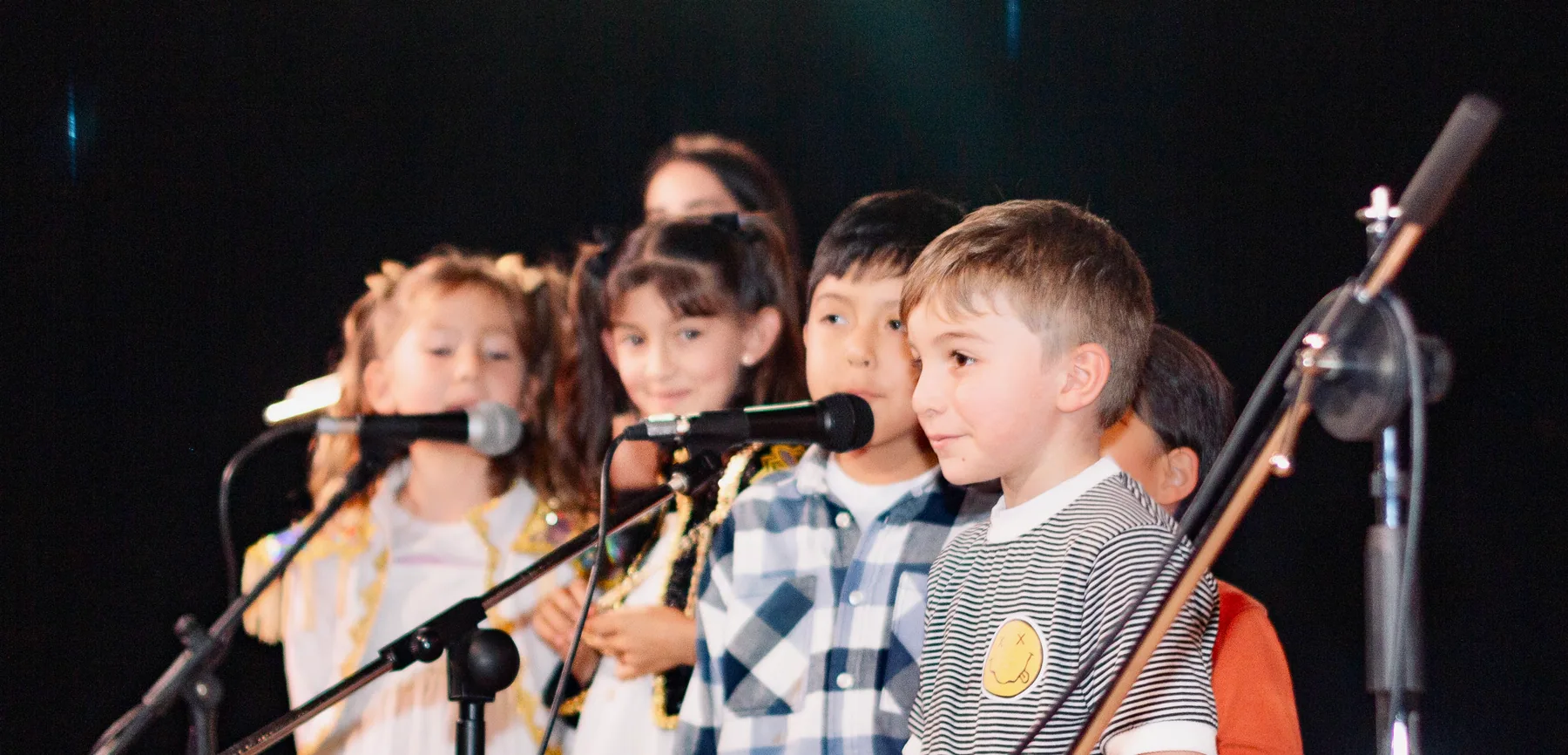 Niños cantando en grupo durante una muestra musical.
